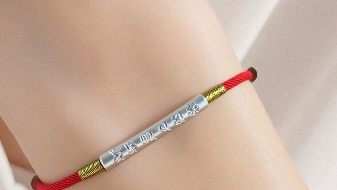 Tibetan-inspired red string bracelet with an engraved mantra tube worn on a wrist