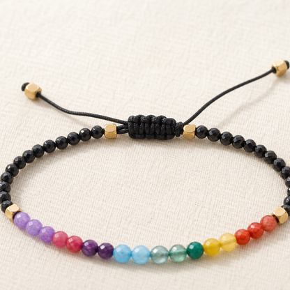 Close view of black braided sliding knot and gold-tone spacers on multicolour bead bracelet