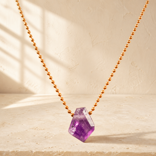 Amethyst necklace on warm ivory stone in natural light