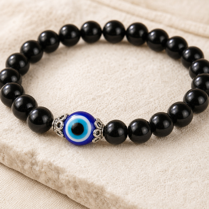 Close-up of the blue-and-white evil eye bead, silver-tone caps, and black obsidian beads