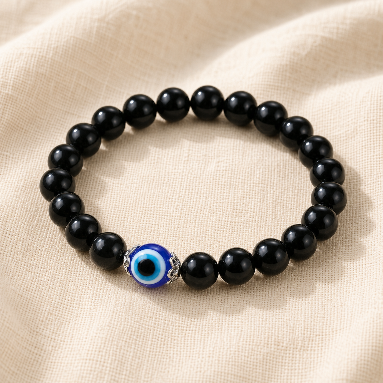 Black obsidian evil eye bracelet with blue-and-white centerpiece on ivory linen