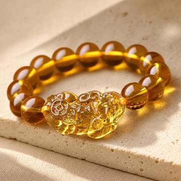 Citrine Pixiu bracelet with translucent golden beads and amber centerpiece on ivory limestone