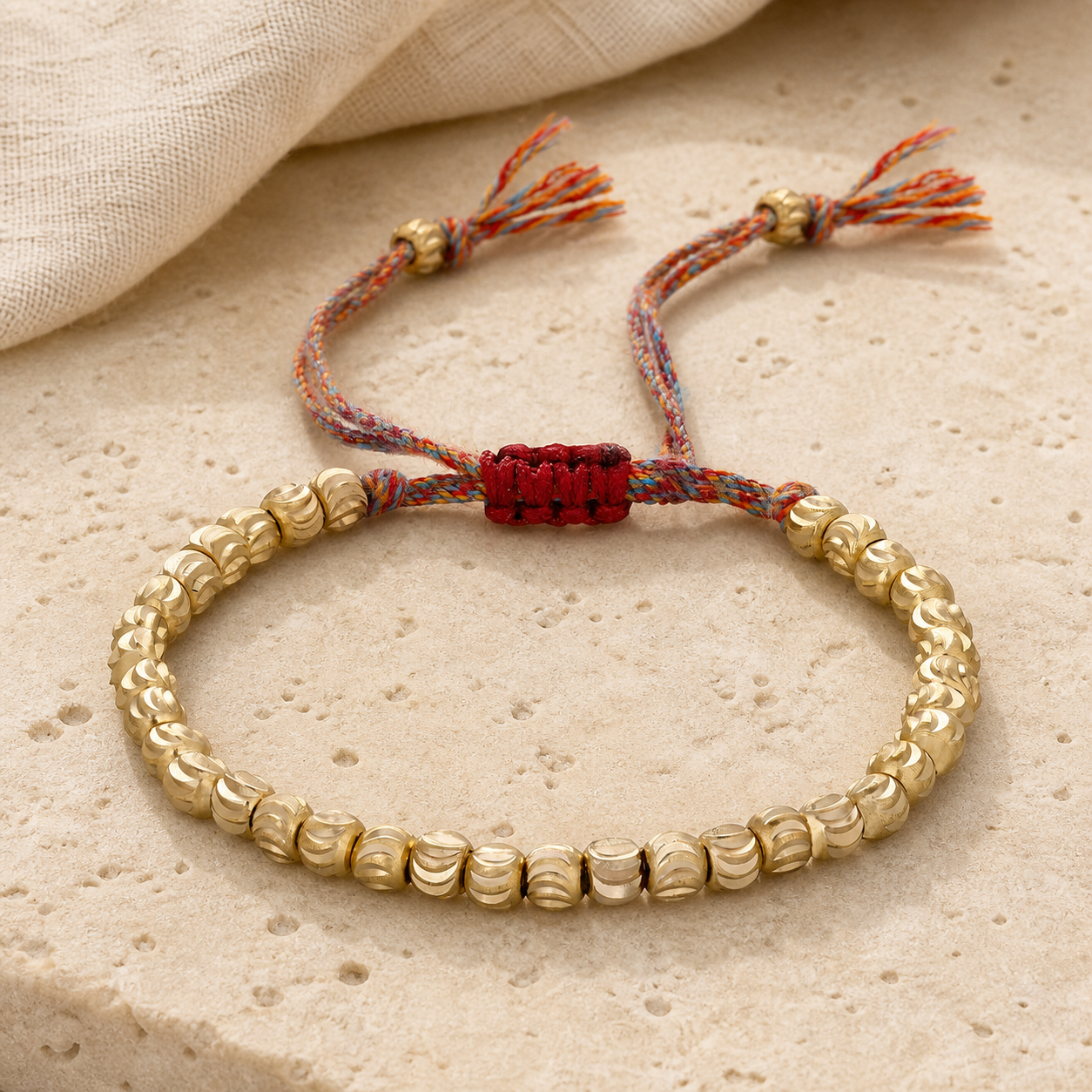 Copper Bead Bracelet close-up showing the red woven sliding clasp, multicolor cord and carved beads