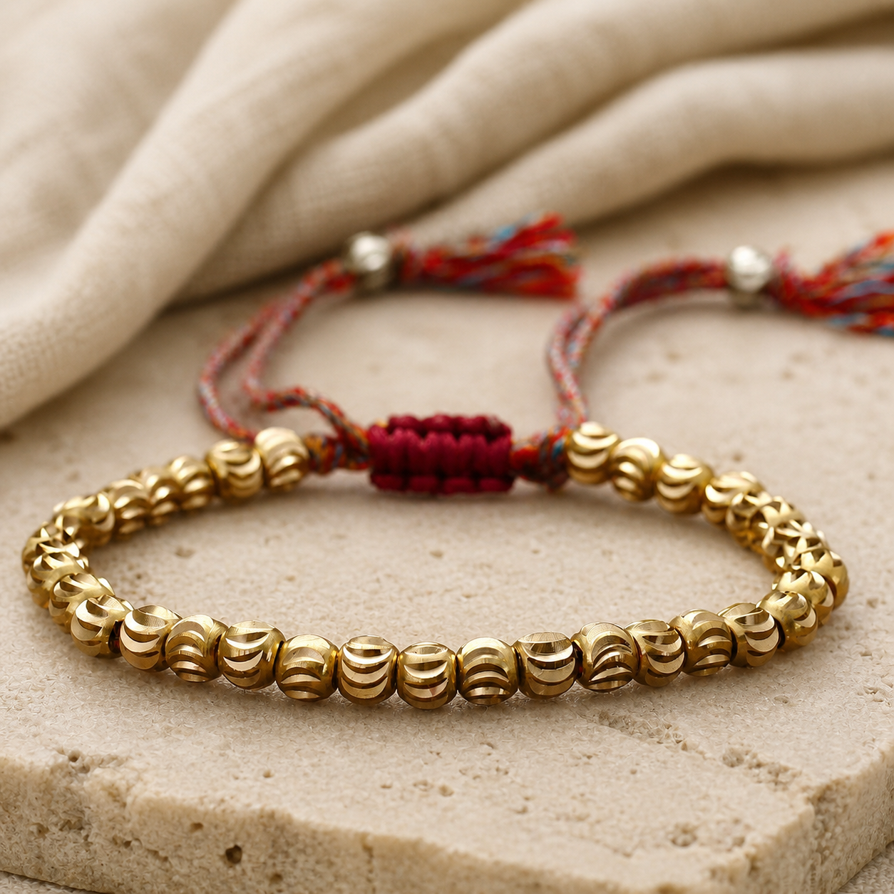 Copper Bead Bracelet hero view with gold-toned carved beads, multicolor cord and red woven clasp