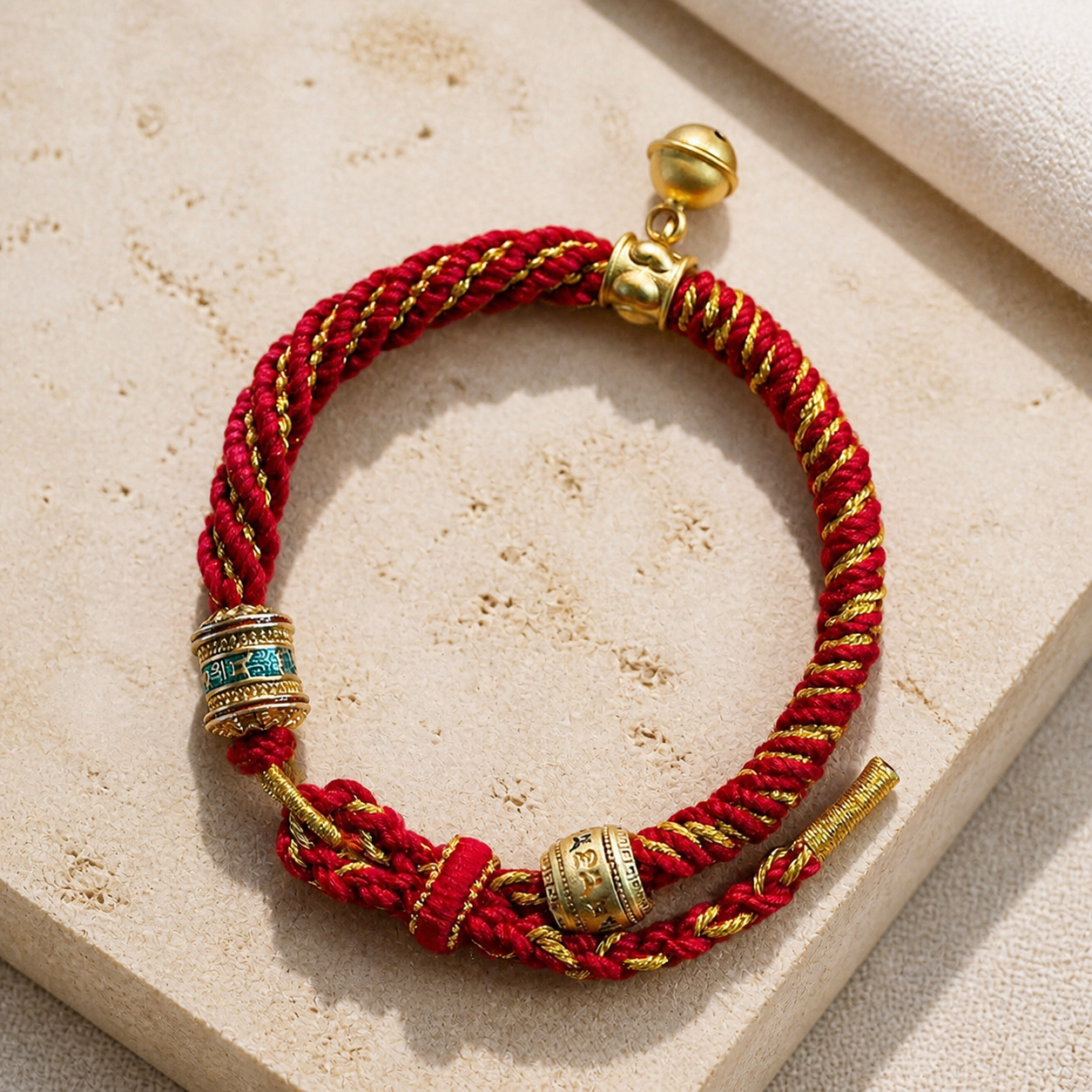 Red and gold woven bracelet on warm ivory stone
