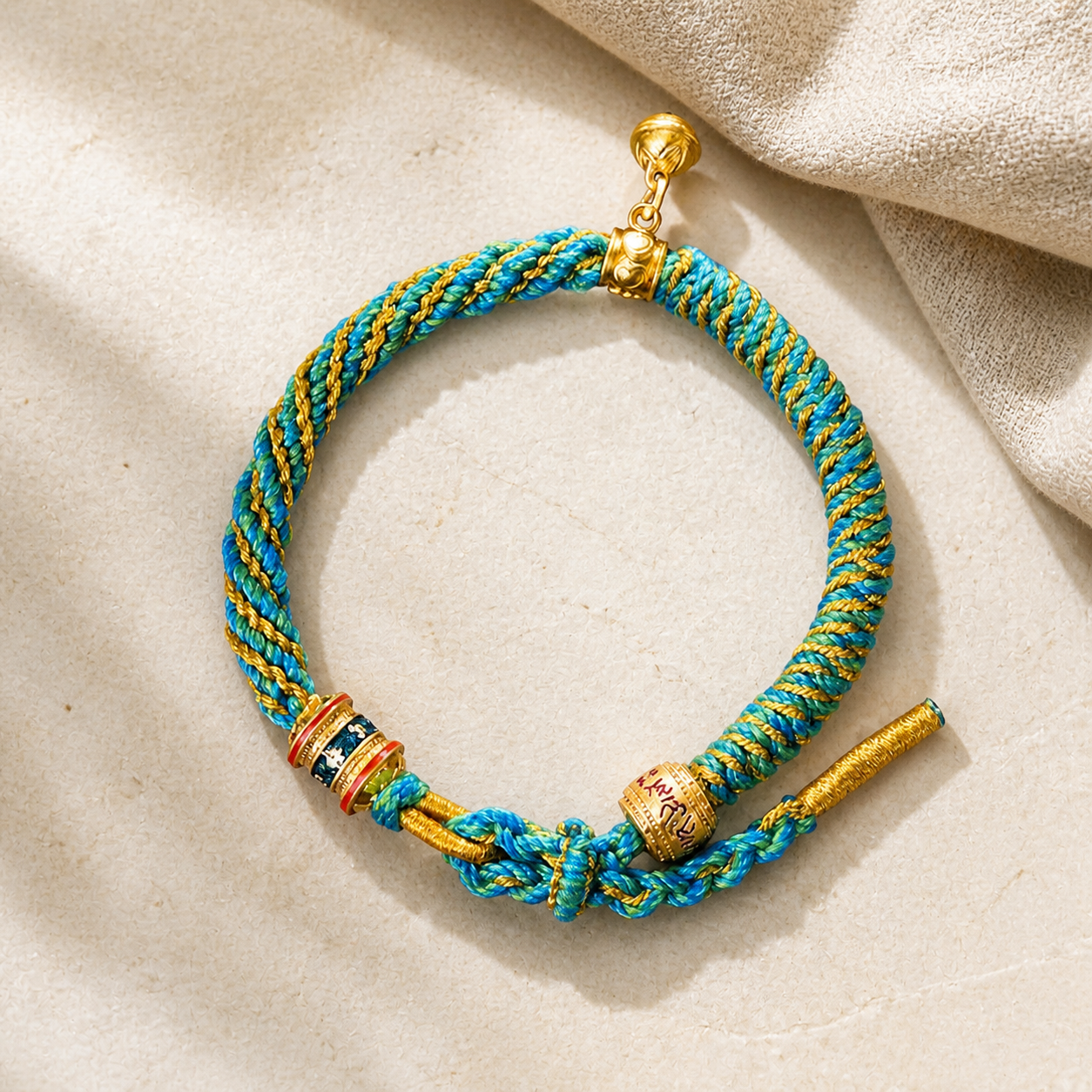 Turquoise and gold woven bracelet on warm ivory stone