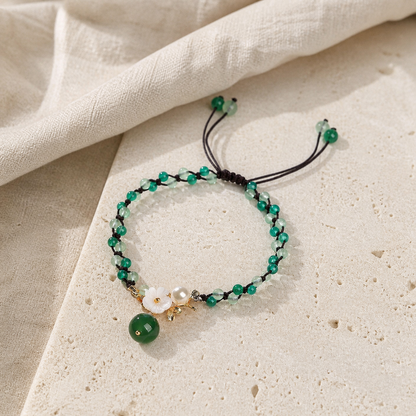 Green jade anklet with flower charm on warm ivory stone