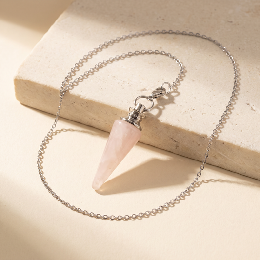 Rose quartz pendulum necklace on warm ivory stone