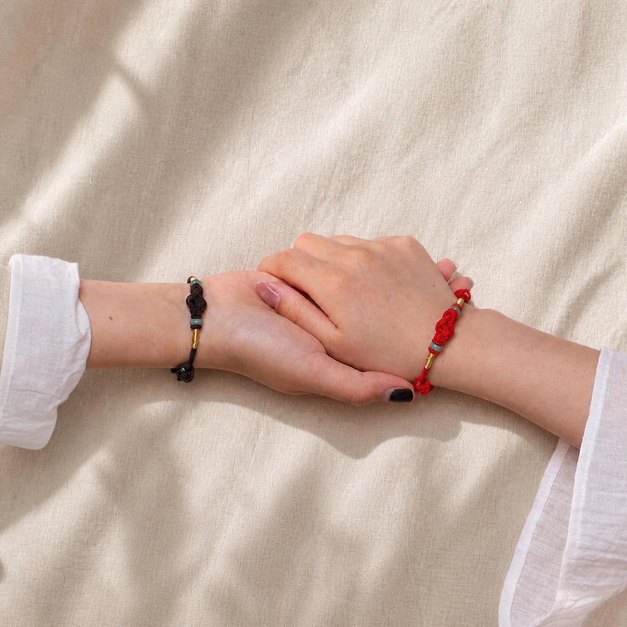 Red and black string jade bracelets worn on two wrists